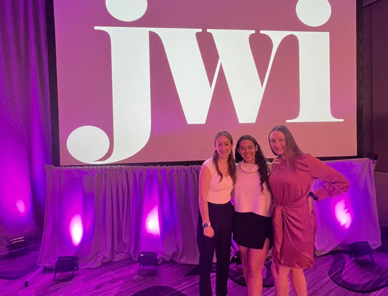 SDT members in front of a large JWI logo