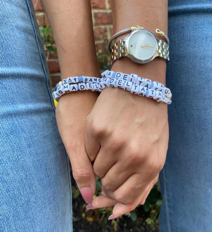 Two hands holding wearing SDT friendship bracelets