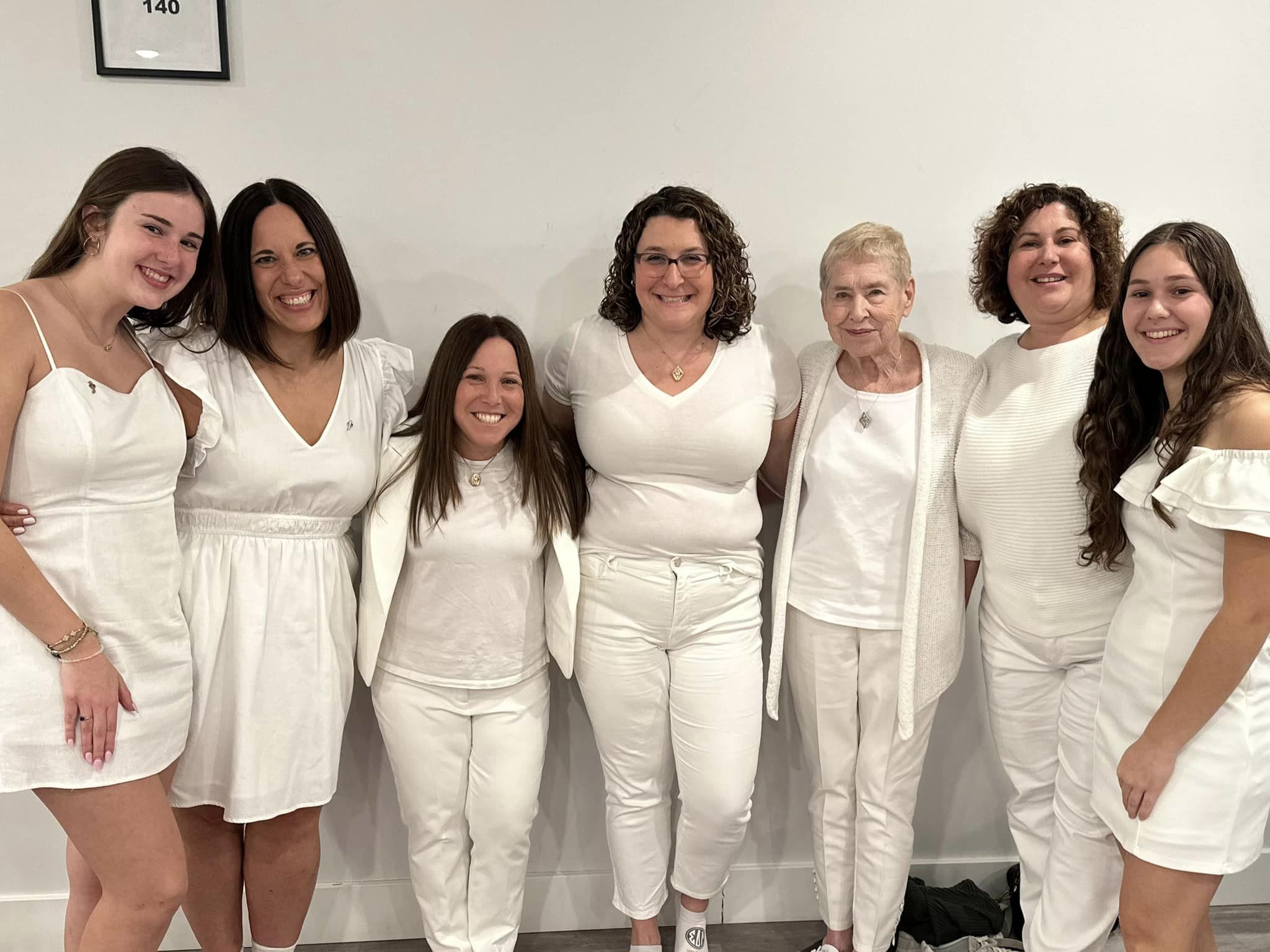 Women smiling in a line wearing white clothing