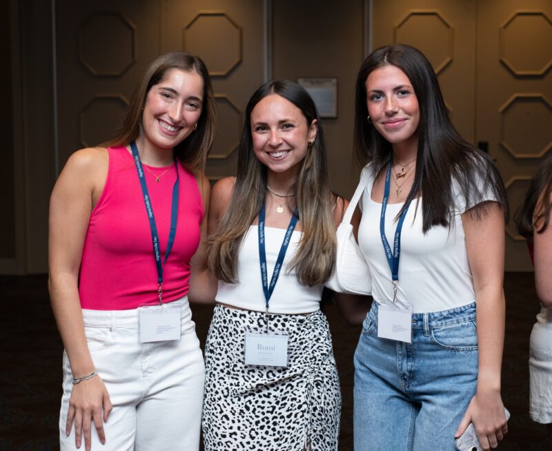 Three girls smiling while wearing conference lanyards